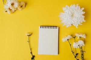 Notizbuch und Blume ist auf gelbem Hintergrund platziert foto