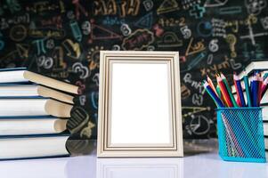 weißer Bilderrahmen, Buch und Buntstifte im Klassenzimmer foto