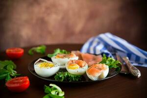 gekocht Eier mit gesalzen rot Fisch, Kräuter und Gewürze im ein Teller . foto