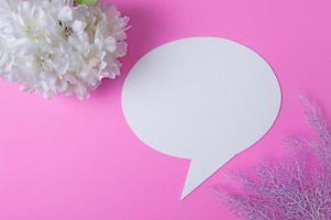 Sprachsymbole aus Papier und Blumen auf rosa Hintergrund. foto