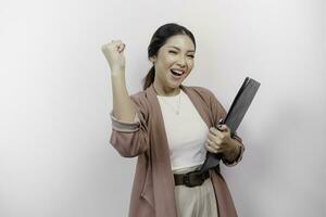 ein jung asiatisch Frau Mitarbeiter mit ein glücklich erfolgreich Ausdruck tragen Strickjacke und halten ein Zwischenablage, isoliert durch Weiß Hintergrund foto