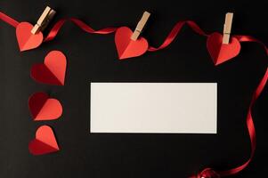 weißes Papier und rotes Herzpapier auf schwarzem Hintergrund geklebt. foto