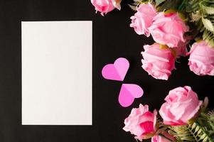 weißes Papier und rosa Blumen auf schwarzem Hintergrund foto