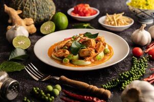 trockenes grünes Curry mit Hühnchen in weißen Tellern auf schwarzem Zement foto