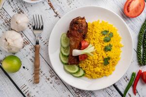 Chicken Biryani in einem Teller mit Gewürzen auf einem weißen Holzboden foto