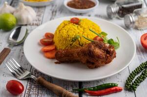 Chicken Biryani in einem Teller mit Gewürzen auf einem weißen Holzboden foto