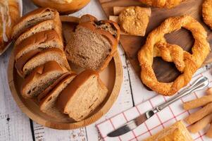 Brotscheiben in einer Holzplatte auf einem weißen Holztisch. foto