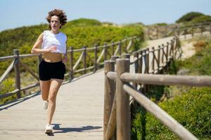 sportlich Frau Laufen entlang Gehweg im Landschaft foto