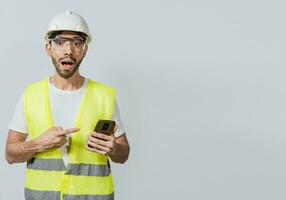 Ingenieur mit und zeigen beim Handy. erstaunt Konstruktion Arbeiter mit und zeigen Handy. überrascht Gesicht Ingenieur mit Zelle Telefon. Konstruktion Ingenieur zeigen beim Telefon Promo foto