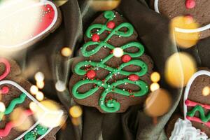 Banner zum Weihnachten und Neu Jahr Lebkuchen. Weihnachten Bäume, Spielzeuge, Schneemänner, Girlanden auf ein Hintergrund von braun Seide Stoff. hell Bokeh. foto