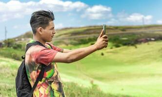 heiter Kerl nehmen ein Foto im das Feld, jung Mann nehmen Fotos im das Feld mit seine Zelle Telefon