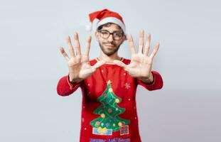 Mann im Weihnachten Hut Zählen Nummer zehn mit Finger. Weihnachten jung Mann Zählen Nummer zehn mit Hände. Konzept von Mann im Weihnachten Kostüm Zählen Nummer zehn isoliert foto