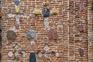 Mauer von ein uralt orthodox Kirche, Monument von alt Backstein Russisch die Architektur mit Textur von Lehm Ziegel, dekoriert mit Einsätze von farbig Steine im das gestalten von Kreuze foto