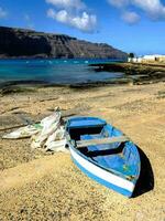 ein Blau Boot sitzt auf das Strand in der Nähe von das Ozean foto