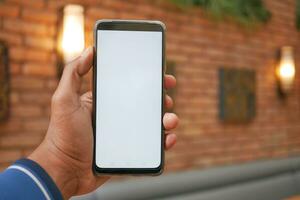 Hand des jungen Mannes mit Smartphone mit grünem Bildschirm im Café foto