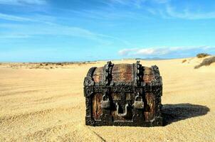 ein alt hölzern Truhe Sitzung auf das Sand im das Wüste foto