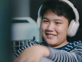 Lebensstil asiatisch wenig Jungs Lächeln verwenden Desktop Stck Computer zu abspielen Fachmann Video Spiele mit Kopfhörer im das Haus, Plaudern mit Freunde, und Unterhaltung foto