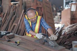 Senior männlicher Tischler arbeitet in einer Holzsägewerksfabrik. foto