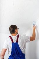 Mann in blauer Gesamtmalerei Wand mit Pinsel foto