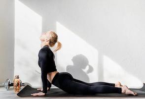 junge sportliche Frau, die zu Hause trainiert oder Yoga streckt