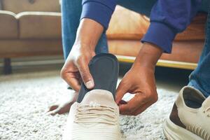 Männer Hand Putten orthopädisch Einlegesohlen im Schuhe foto