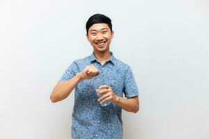 positiv asiatisch Mann Blau Hemd glücklich Lächeln und Geste öffnen Deckel von Wasser Flasche im seine Hand isoliert foto