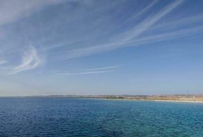 breit Aussicht zu das Strand Blau Meer und Sanft Wolken beim das Blau Himmel foto