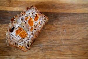 Stück von ganze Korn Brot mit kandiert Früchte auf ein hölzern Hintergrund, Kopieren Raum foto