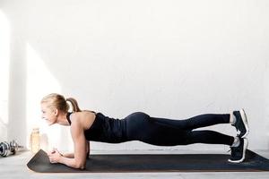 junge blonde Frau beim Training im Stehen in Plankenposition
