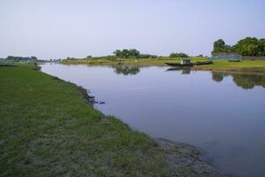 Kanal mit Grün Gras und Vegetation reflektiert im das Wasser in der Nähe von Padma Fluss im Bangladesch foto