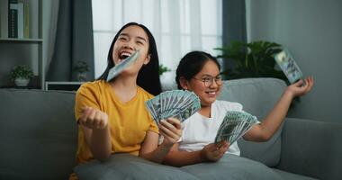 Porträt von ein jung Frau und Teenager Mädchen genießen Streuung Kasse Rechnungen auf ein Sofa im das Leben Zimmer beim heim. foto