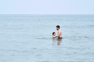 Papa Theaterstücke mit seine Söhne im das Meer. foto