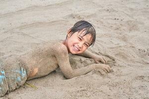 ein Junge ist Lügen im das Sand nach Schwimmen im das Meer. foto