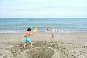 Kinder graben ein Loch im das Sand auf das Strand. foto