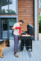 ein Mann Köche auf ein Grill auf das Veranda. foto