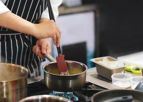 Koch kocht, Koch bereitet Essen zu, Koch dekoriert Gericht in der Küche foto