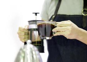 Barista gießt Kaffee aus einer French Press in die Tasse foto