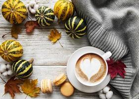 Tasse Kaffee, trockene Blätter und Schal auf einem Tisch foto