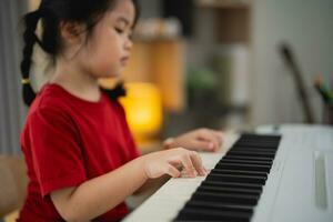 schließen oben Hand, glücklich wenig asiatisch süß Baby Mädchen Lächeln spielen Lernen online Klavier Musik- im Leben Zimmer beim heim. das Idee von Aktivitäten zum Kind beim Zuhause während Quarantäne. Musik- Lernen lernen. foto