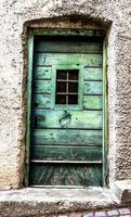 grüne Holztür mit wetterbeschädigtem Fenster in San Martino di Castrozza, Trento, Italien foto