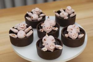 dekorierte Bonbons, glückliche süße rosa Schweine, die im Schlamm spielen foto