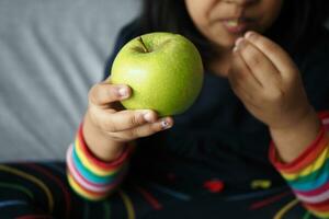 Kind beißen ein Grün Apfel schließen oben foto