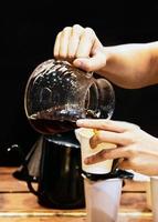 Barista kocht Kaffee, Barista gießt Tropfkaffee ins Glas