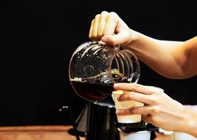 Barista kocht Kaffee, Barista gießt Tropfkaffee ins Glas foto