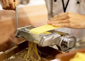 Koch macht Pasta mit einer Maschine, hausgemachte frische Pasta foto