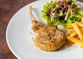 Schweinekotelettsteak mit Salat und Pommes frites foto