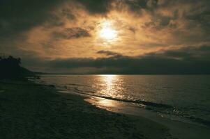 Sonnenuntergang auf das Westen Strand auf das baltisch Meer. Wellen, Strand, wolkig Himmel und Sonnenschein foto