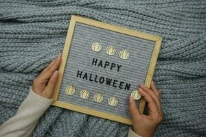 Damen Hände halt ein Tafel mit das Text glücklich Halloween foto