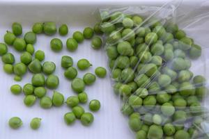 grüne Erbsen sind in einer Tüte auf einem weißen Tablett. frisches Gemüse ernten foto
