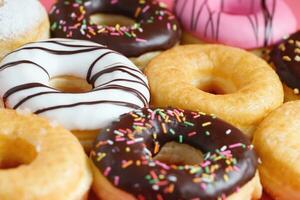 sortiert Donuts mit Schokolade Glasur, Belag Sträusel Donuts bunt Vielfalt und Vielfalt von Aromen mischen von multi farbig Süss Donuts mit gefrostet bestreut auf Rosa Hintergrund. oben Aussicht foto